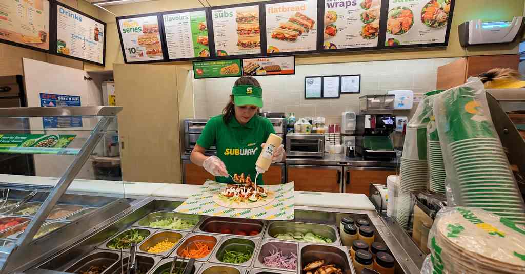 subway wrap being made with chicken salad and sauce